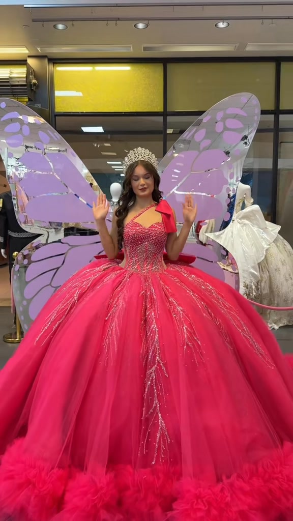 Pink quinceañera gown with decorative wings.